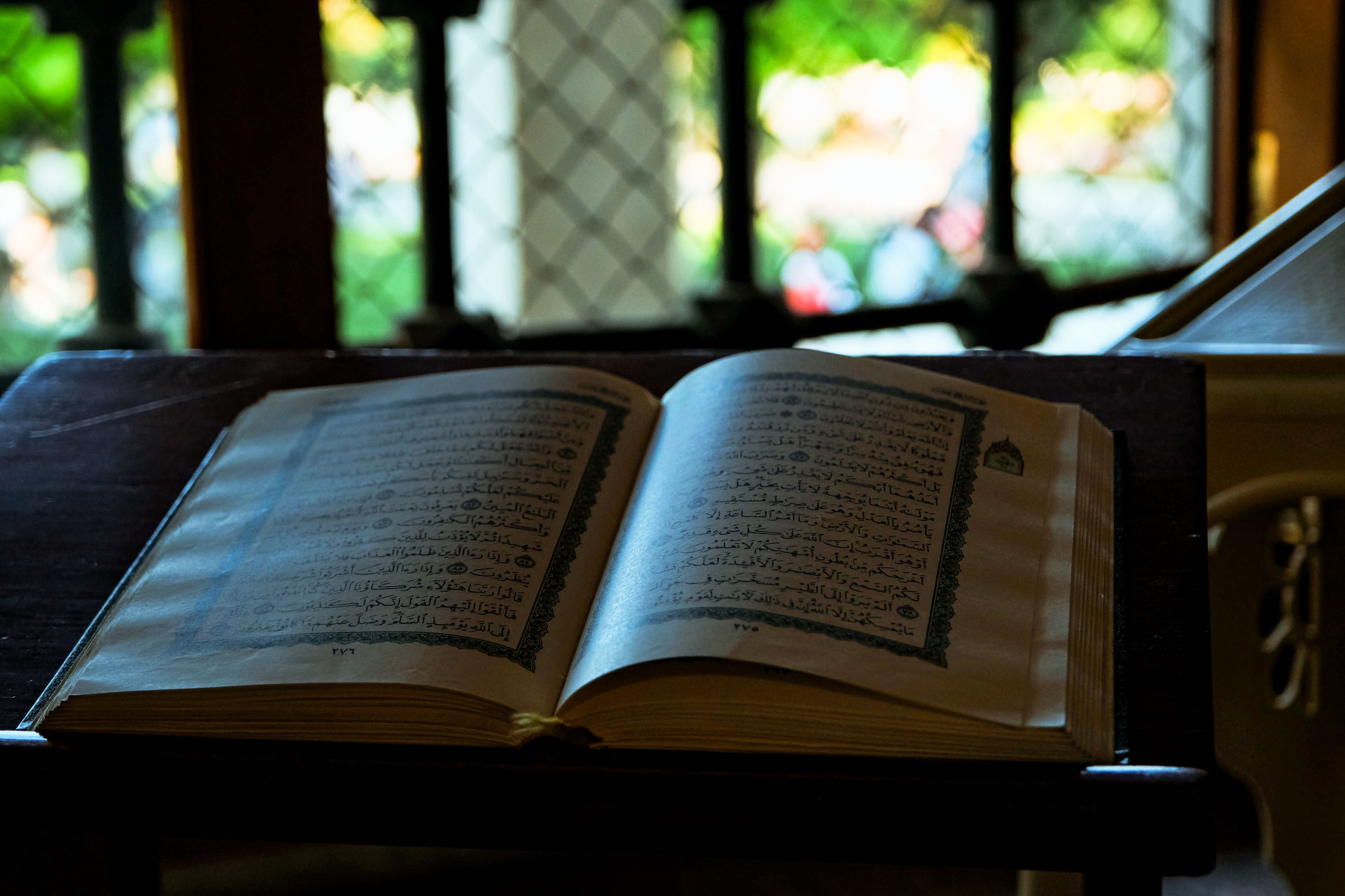 Open Quran on a wooden stand in a dimly lit, contemplative room