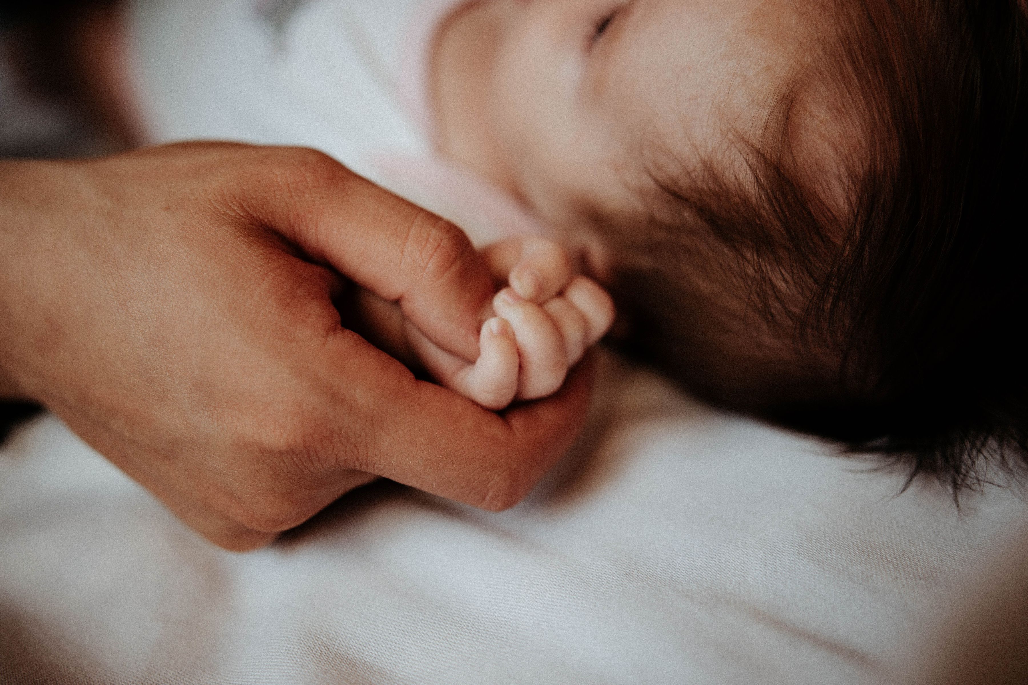 Father gently holding his newborn baby's hand