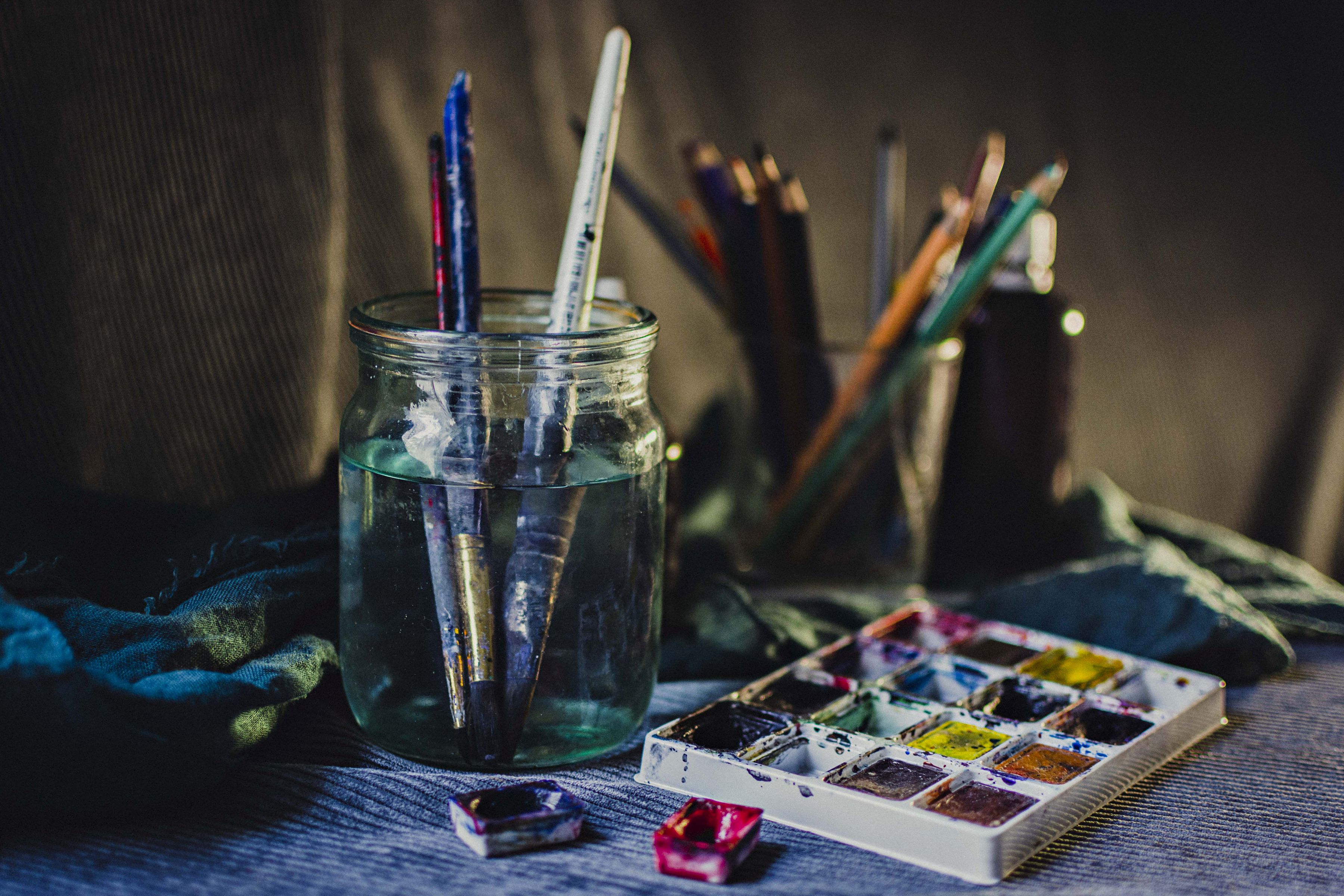 Watercolour palette and paintbrushes soaked in water, a creative still life